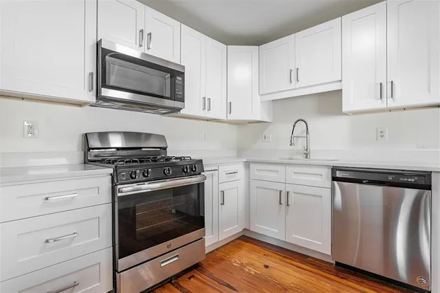 a kitchen with cabinets stainless steel appliances a sink and wooden floor