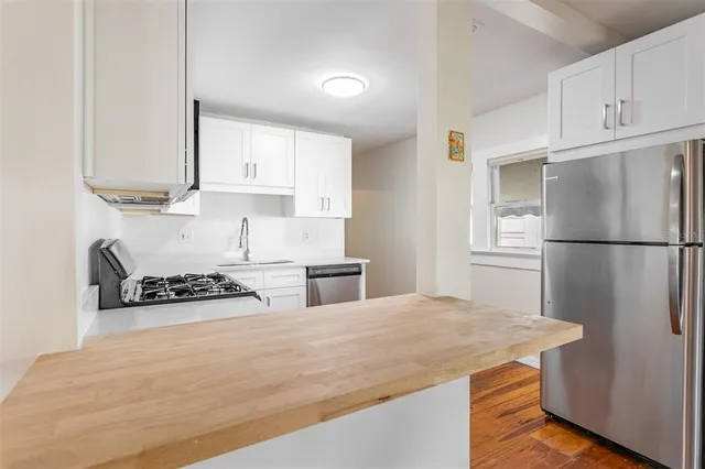 a kitchen with granite countertop a refrigerator a stove a sink and white cabinets