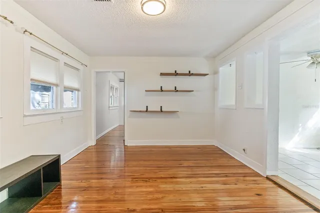 a view of empty room with wooden floor and fan