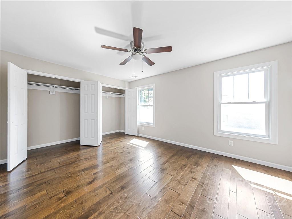 202 Sycamore Cv Road, Unit 1 Asheville, NC 28803 - Photo 5 of 10 an empty room with wooden floor fan and windows