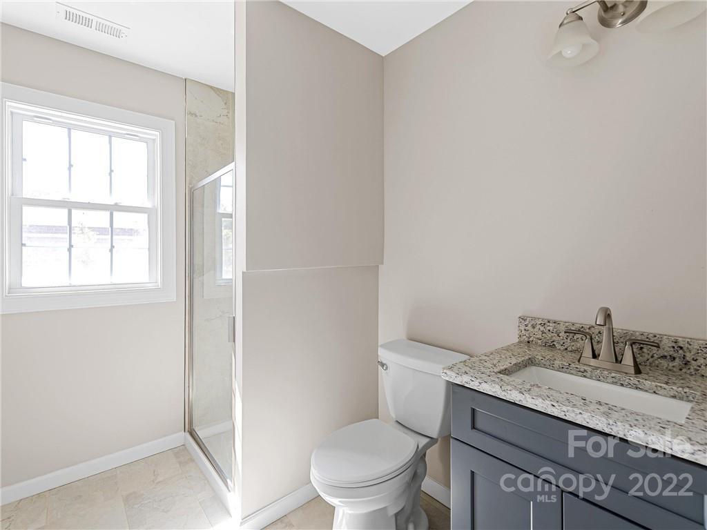 202 Sycamore Cv Road, Unit 1 Asheville, NC 28803 - Photo 6 of 10 a bathroom with a granite countertop sink a toilet and a window