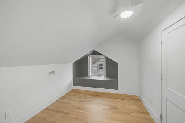 a view of an empty room with a window and wooden floor