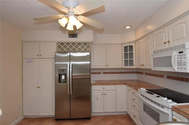 a kitchen with stainless steel appliances granite countertop a refrigerator a sink and white cabinets