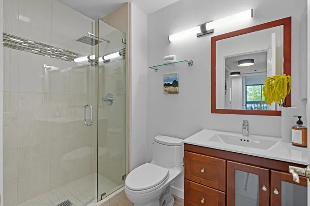 a bathroom with a toilet a sink a glass door a shower a mirror and vanity