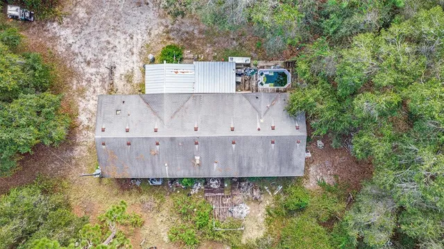 an aerial view of residential house with outdoor space and trees all around