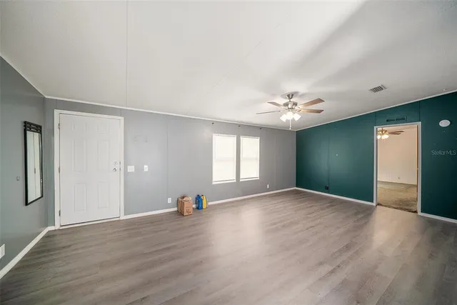 a view of an empty room with window and wooden floor