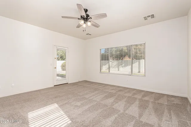 an empty room with windows and fan