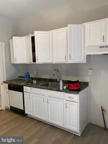 a kitchen with granite countertop white cabinets and sink
