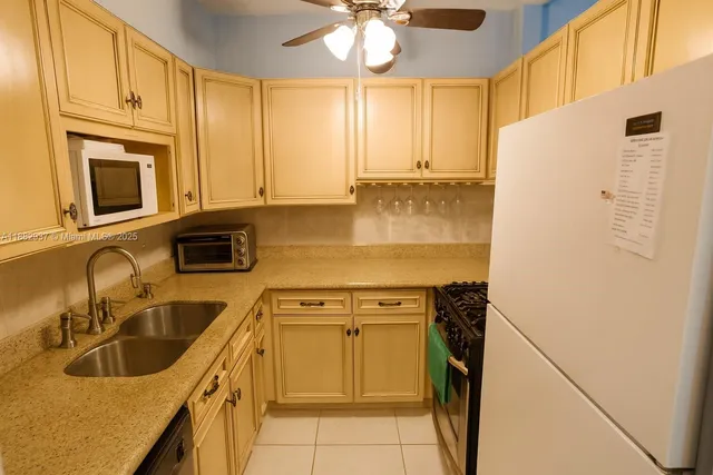 a kitchen with stainless steel appliances granite countertop a sink a stove a refrigerator a washer dryer and white cabinets