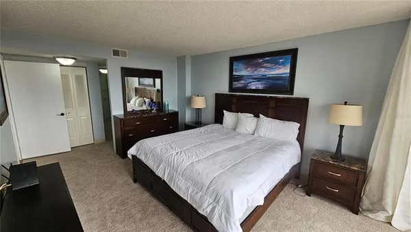 a bedroom with a bed and a lamp on dresser