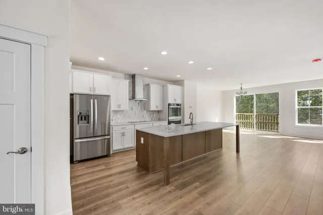 a large kitchen with a center island wooden floor and stainless steel appliances