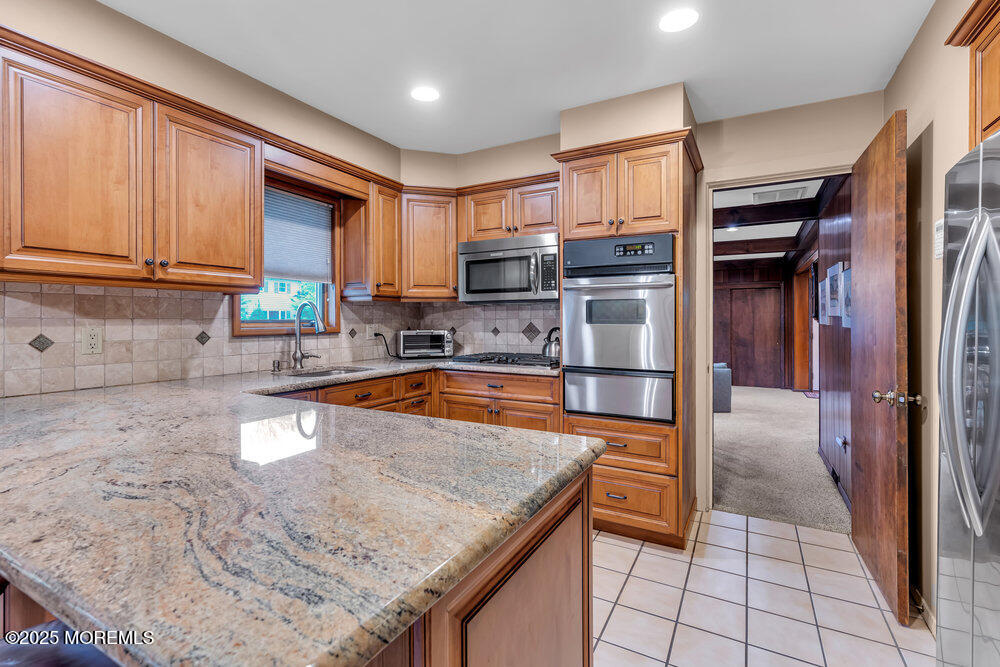2308 Logan Road Asbury Park, NJ 07712 - Photo 14 of 37 a kitchen with stainless steel appliances granite countertop a refrigerator a stove and a sink with wooden cabinets