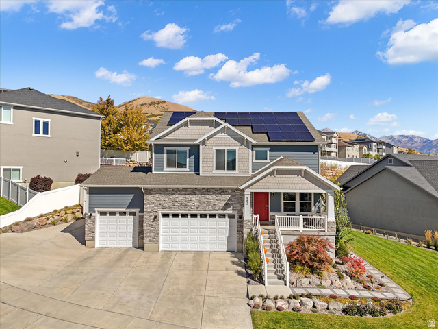 882 Spring Dew Lane Lehi, UT 84048 - Photo 2 of 46 View of front of property with a mountain view, roof mounted solar panels, stone siding, covered porch, and driveway