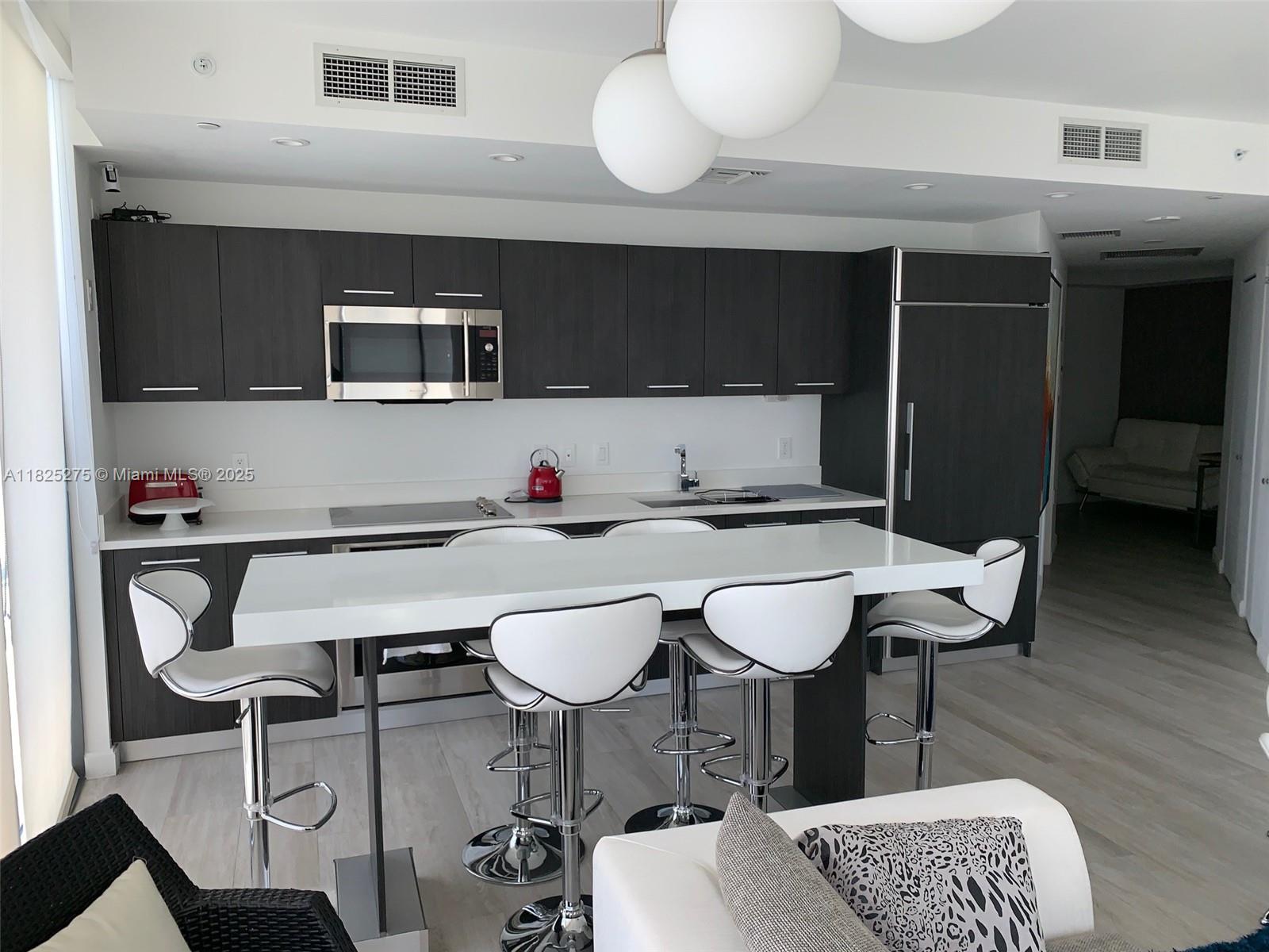 55 Southwest 9th Street, Unit 2706 Miami, FL 33130 - Photo 4 of 8 a kitchen with stainless steel appliances kitchen island granite countertop a table and chairs
