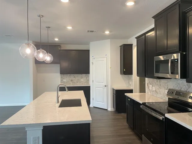 a kitchen with stainless steel appliances granite countertop a sink a stove and a wooden floors