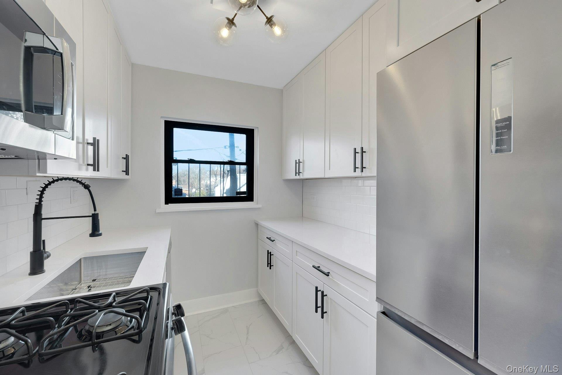 64 Kensington Road, Unit 1B Bronxville, NY 10708 - Photo 4 of 21 Kitchen with stainless steel appliances, white cabinetry, and light stone counters