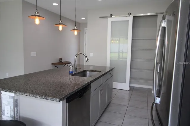 a kitchen with stainless steel appliances granite countertop a sink and a refrigerator