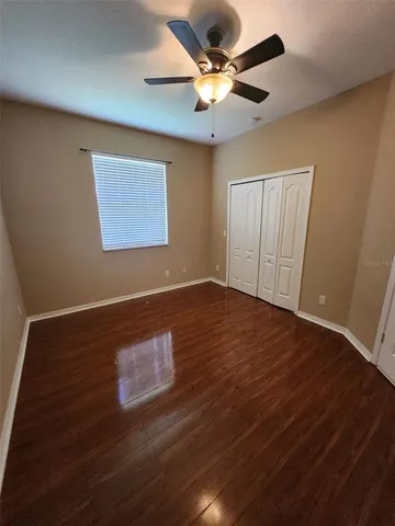a view of a room with wooden floor and a ceiling fan