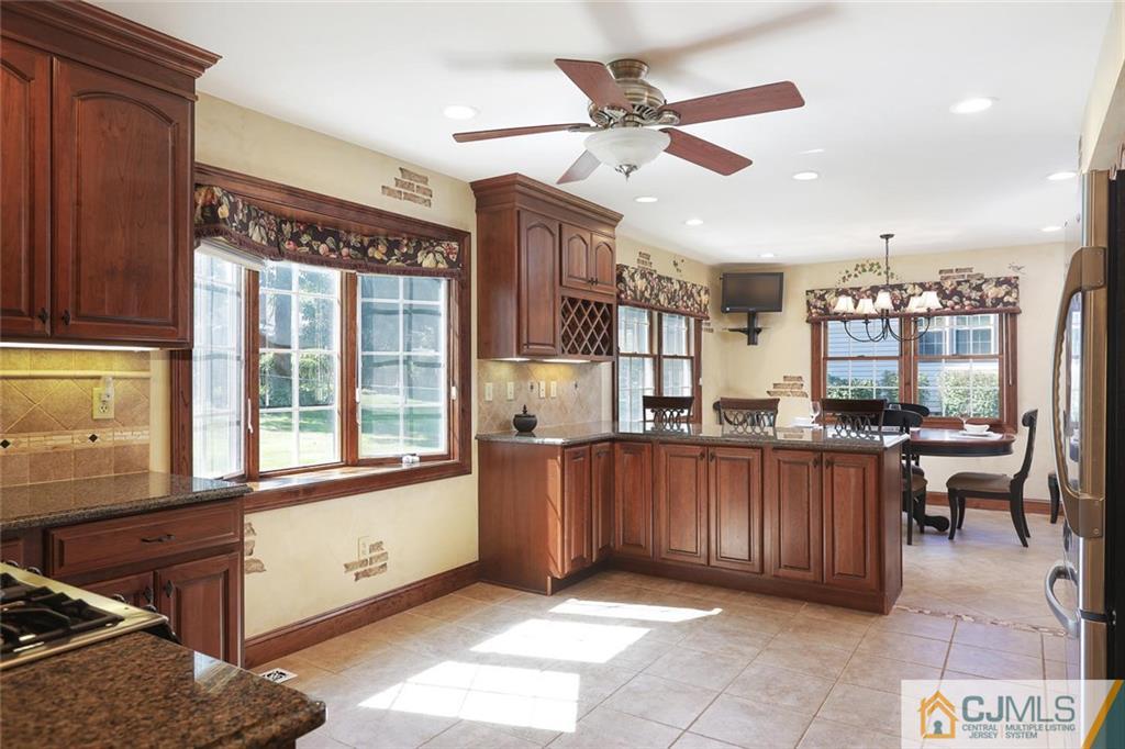 203 Normandy Road Edison, NJ 08820 - Photo 9 of 32 a kitchen with stainless steel appliances kitchen island granite countertop a refrigerator oven a sink a dining table and chairs with wooden floor