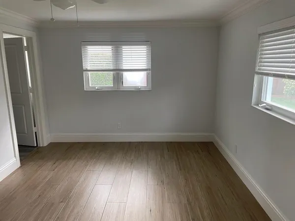 an empty room with wooden floor and windows