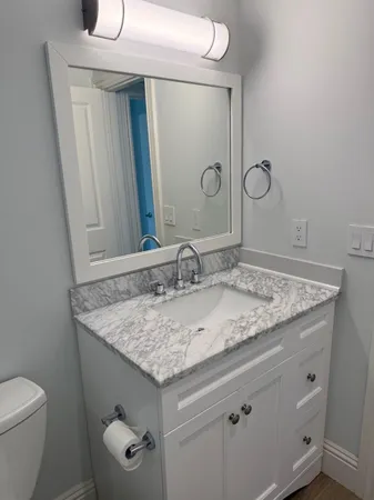 a bathroom with a granite countertop sink and a toilet