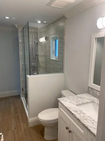 a bathroom with a granite countertop sink a toilet a mirror and shower