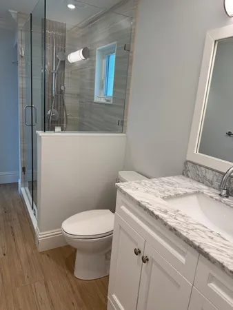 a bathroom with a granite countertop toilet sink and mirror