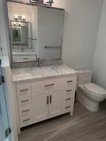 a bathroom with a granite countertop toilet and mirror