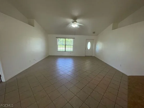 an empty room with windows and chandelier fan