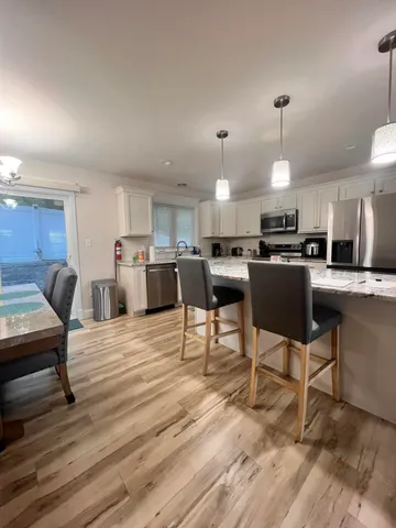 a kitchen with stainless steel appliances kitchen island granite countertop a dining table chairs refrigerator and sink