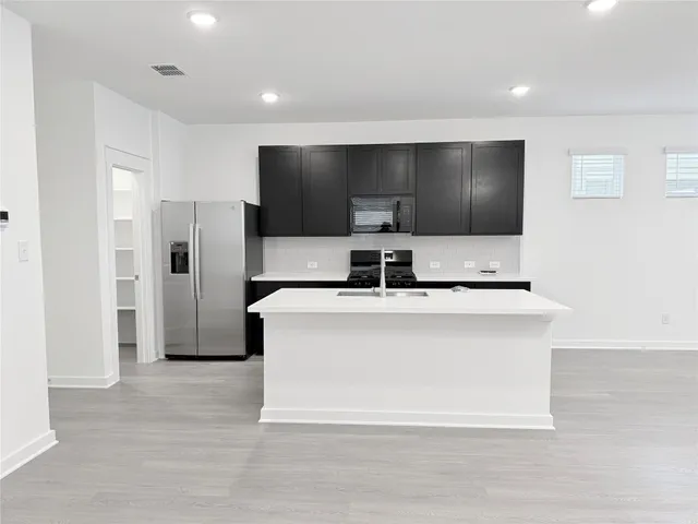 a living room with stainless steel appliances kitchen island granite countertop a refrigerator stove and oven