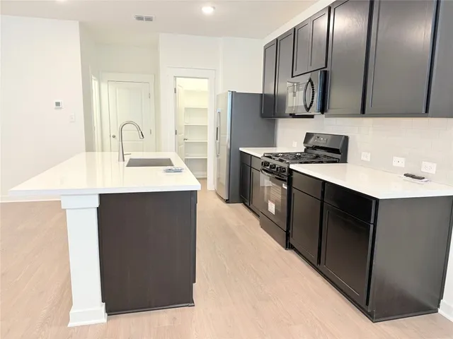a kitchen with stainless steel appliances granite countertop a sink stove and refrigerator