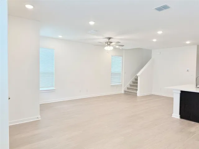an empty room with chandelier fan and windows