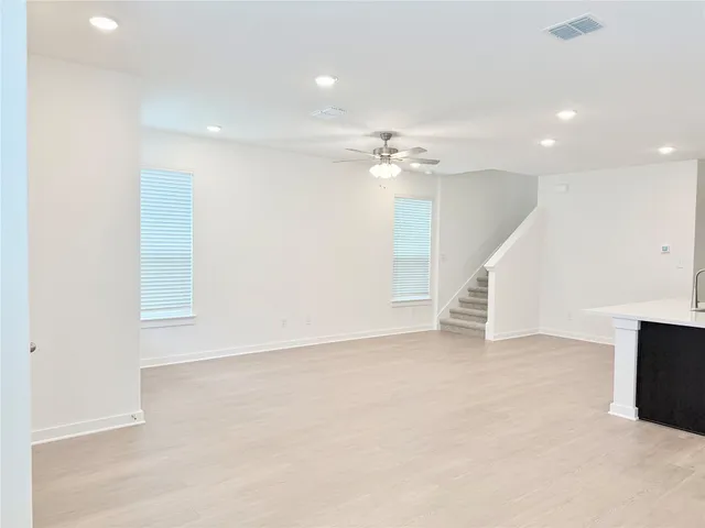 an empty room with chandelier fan and windows