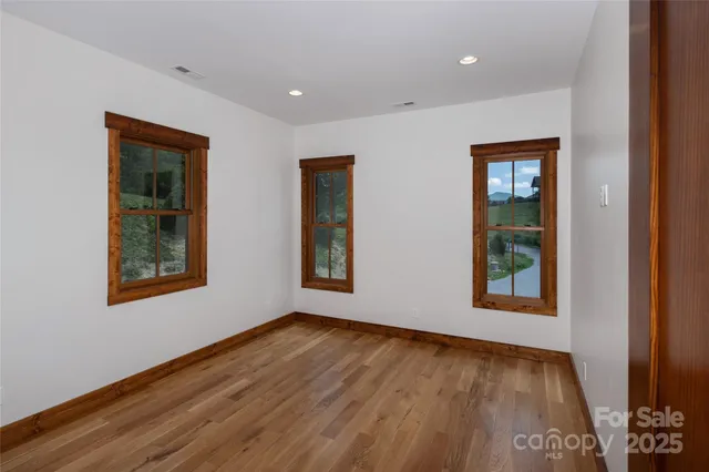 a view of an empty room with window and wooden floor