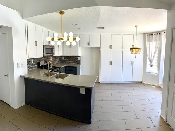 a kitchen with kitchen island granite countertop a sink cabinets and stainless steel appliances