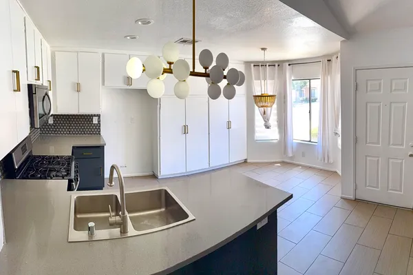 a kitchen with white cabinets and chandelier