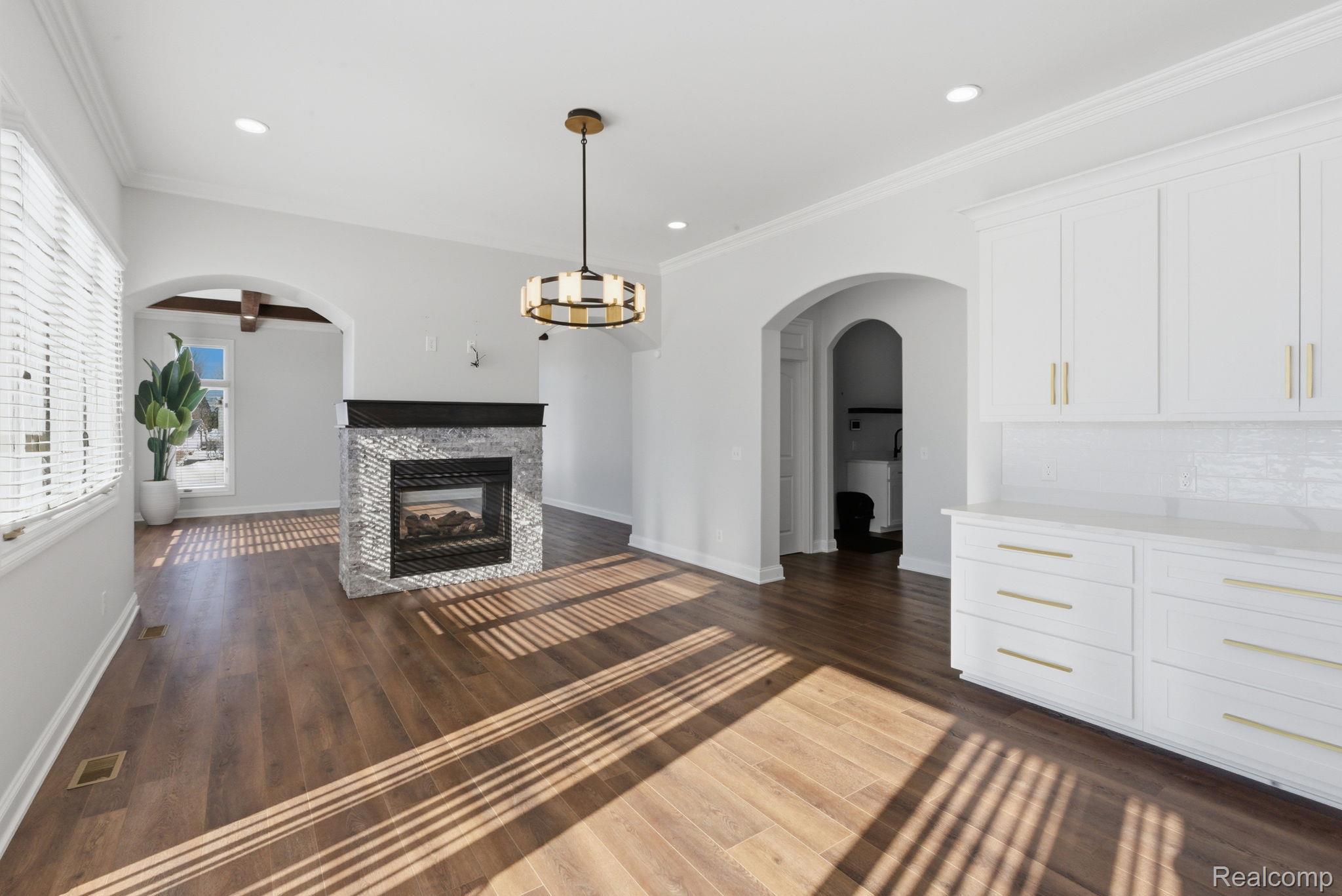 8844 Ridge Drive Washington, MI 48095 - Photo 3 of 51 Unfurnished living room with arched walkways, a stone fireplace, dark wood finished floors, crown molding, and a chandelier