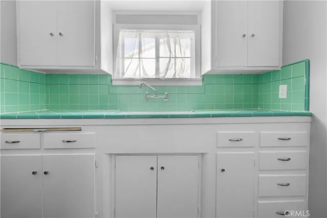a view of a kitchen with white cabinets and a window