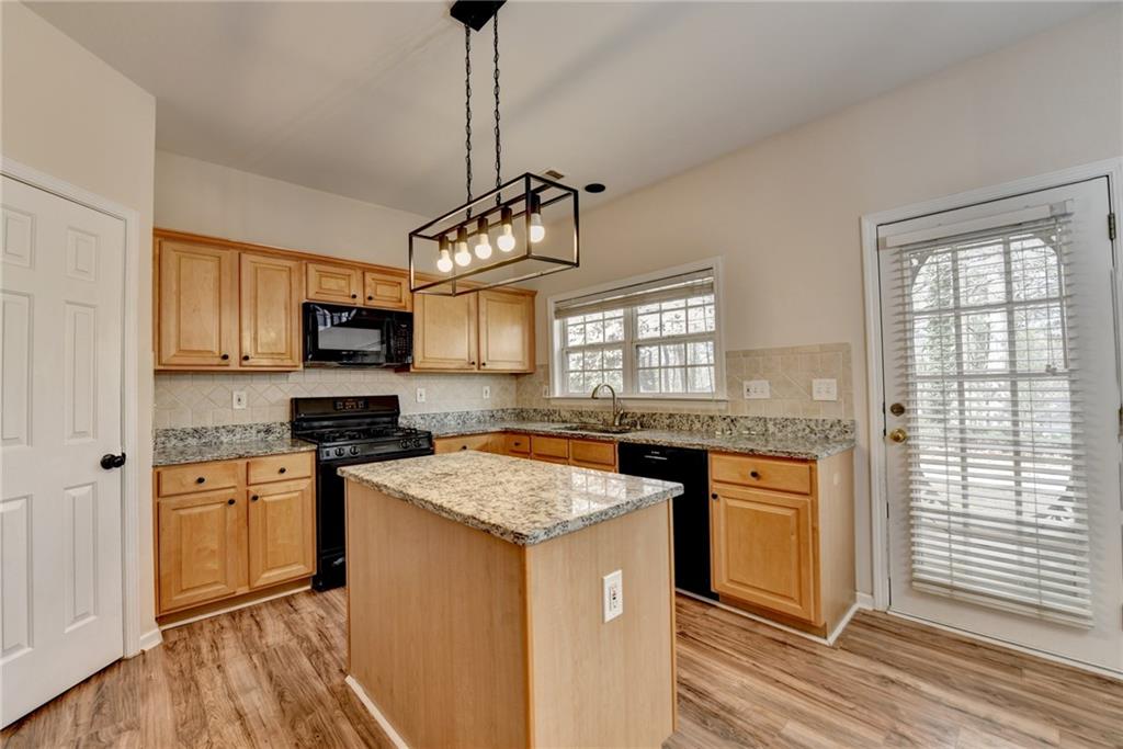 100 Hawnley Trc Northwest Suwanee, GA 30024 - Photo 24 of 58 a kitchen with stainless steel appliances granite countertop stove a sink a refrigerator a microwave oven with white cabinets and wooden floor