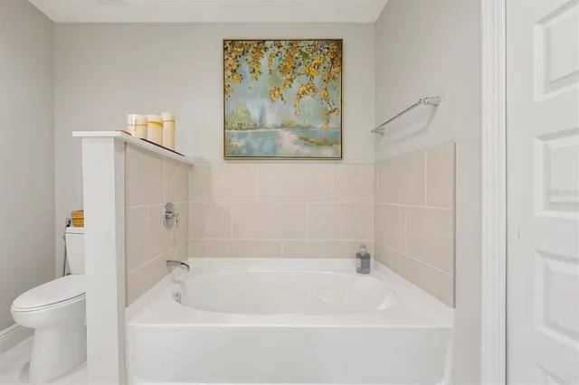 a white bath tub sitting next to a white toilet and vanity