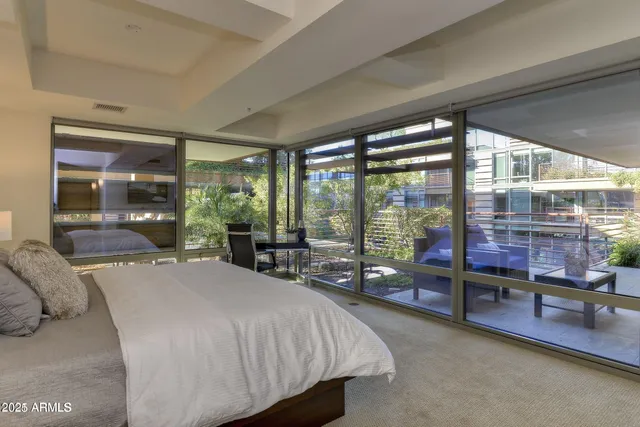 a bedroom with a large bed and large windows with view of balcony