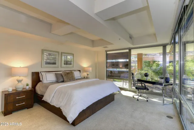 a bedroom with a bed a table and large window