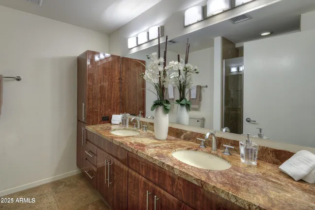 a bathroom with double vanity and a mirror