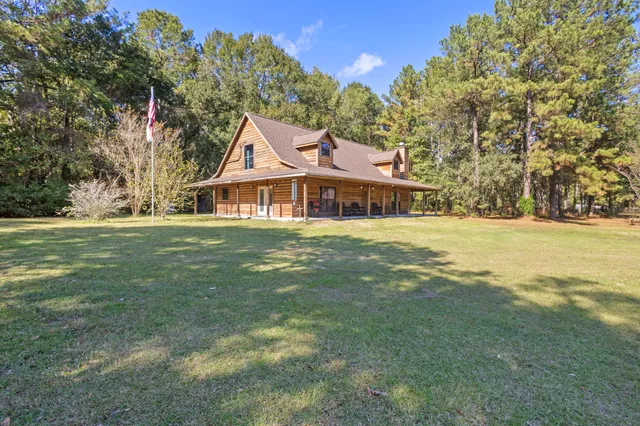a view of a house with a big yard and large trees