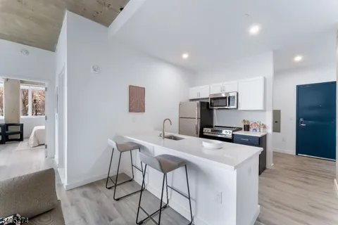 a kitchen with stainless steel appliances a microwave a stove a refrigerator a sink a table and chairs