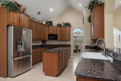 a kitchen with stainless steel appliances granite countertop a refrigerator a stove and a sink