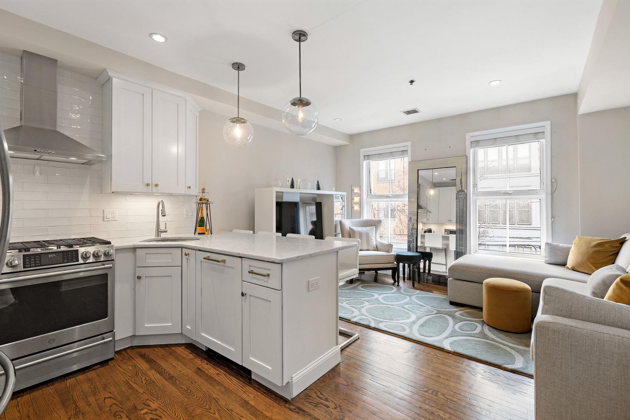 501 9th Street, Unit 309 Hoboken, NJ 07030 - Photo 3 of 18 a kitchen with stainless steel appliances granite countertop a stove top oven a sink dishwasher a dining table and chairs with wooden floor