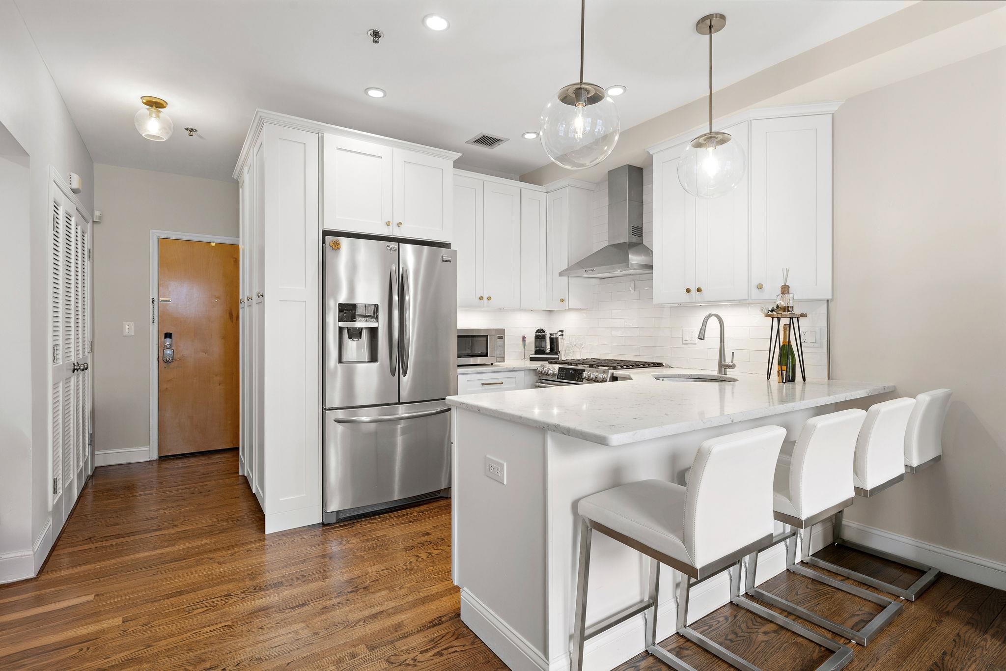 501 9th Street, Unit 309 Hoboken, NJ 07030 - Photo 4 of 18 a kitchen with stainless steel appliances granite countertop a refrigerator a sink dishwasher a stove and white cabinets with wooden floor