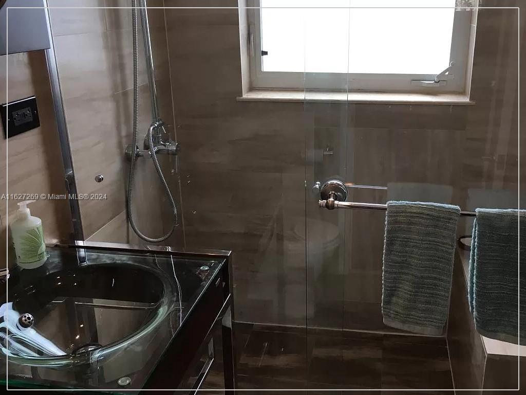 8818 Abbott Avenue Surfside, FL 33154 - Photo 19 of 28 a bathroom with a sink and mirror